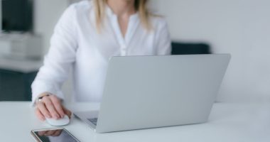 pexels-photo-2265488-2265488 A woman working at a desk using a laptop and smartphone, exemplifying remote work.